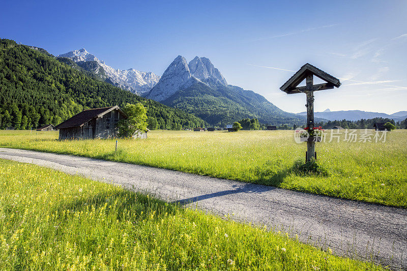 在鲜花草地上的路边神殿在Zugspitze - Garmisch Partenkirchen前面